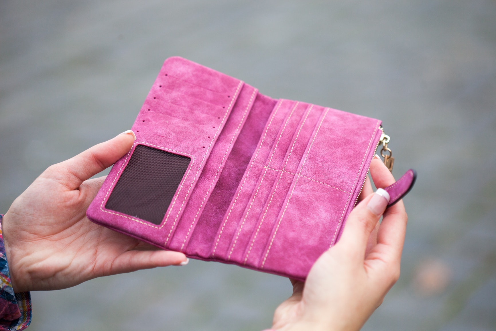 Kobiece dłonie trzymające pusty różowy portfel